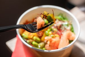 Poke bowl with rice and salmon in craft packaging